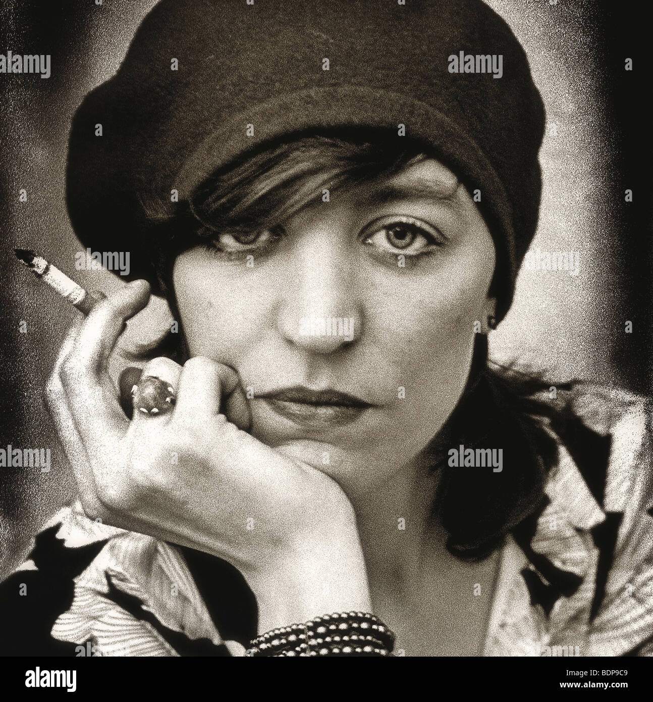 Close up of a middleaged woman wearing a hat and smoking a cigarette looking sternly at the camera Stock Photo