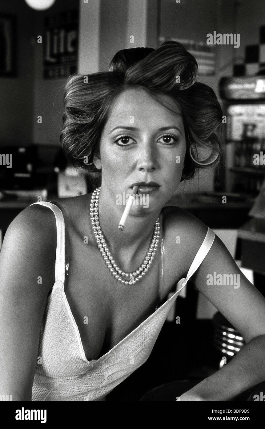 A young woman with rollers in her hair smoking a cigarette Stock Photo