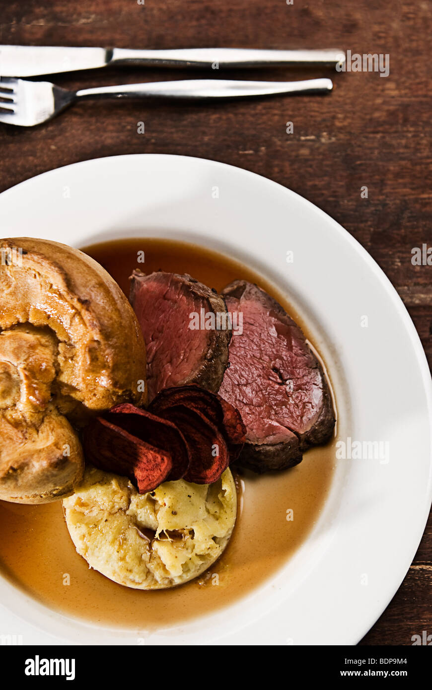 A roast beef with mash potato, yorkshire pudding, beetroot chips and