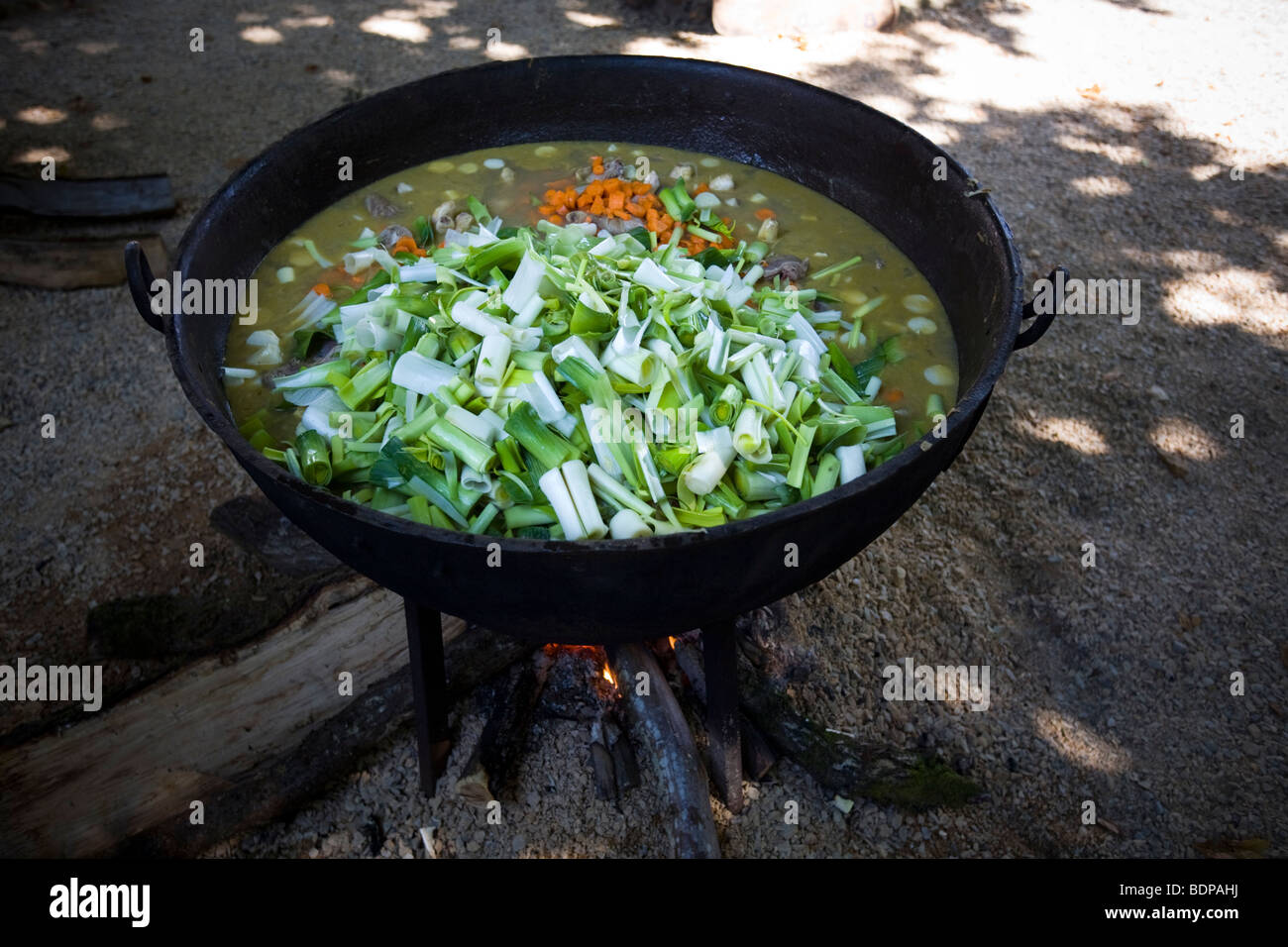 Wood fire cooking of a vegetable soup in a pot.  Cuisson au feu de bois d'une soupe de légumes dans une marmite. Stock Photo