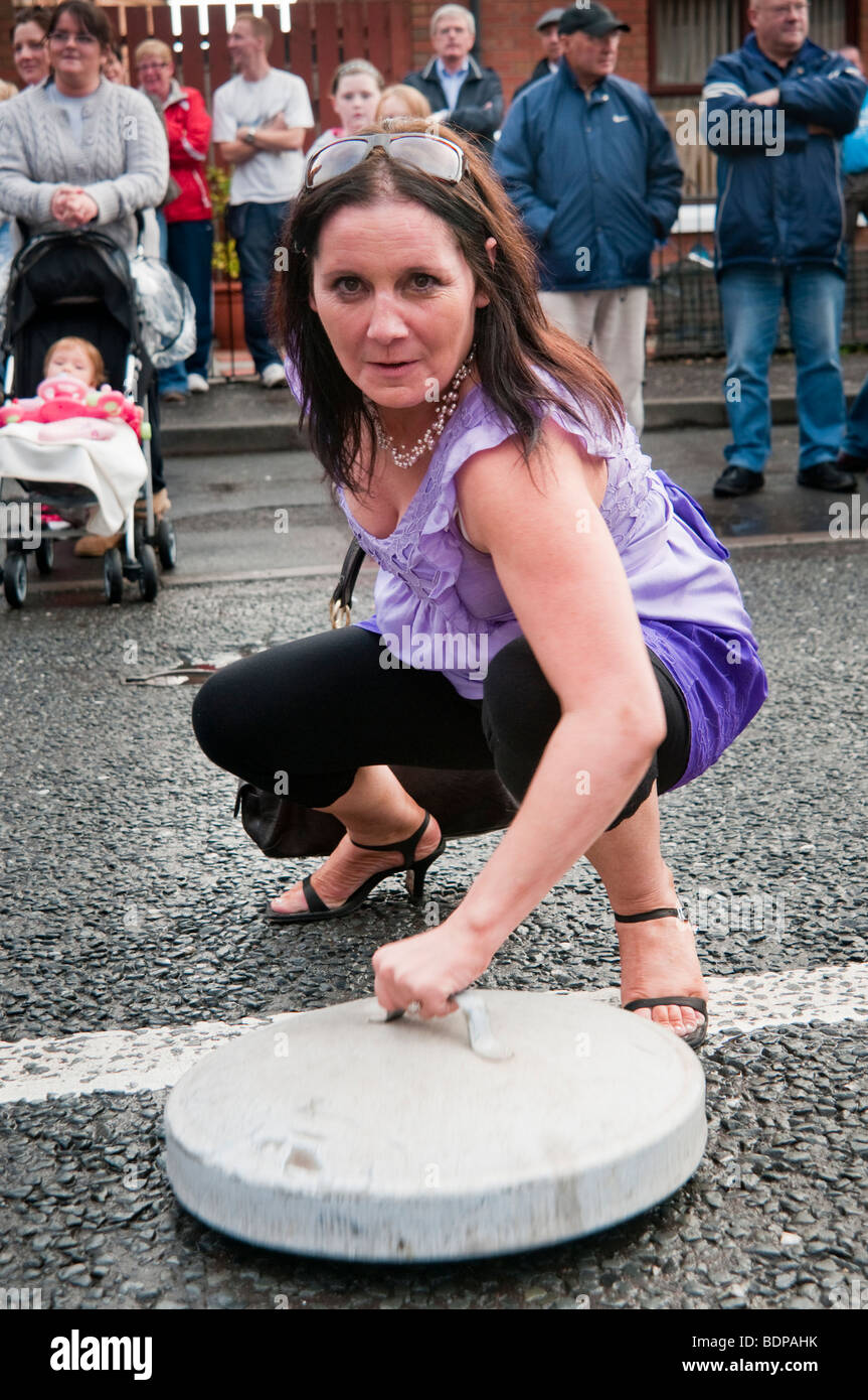 Woman bangs bin lid on street to make a loud noise. Stock Photo
