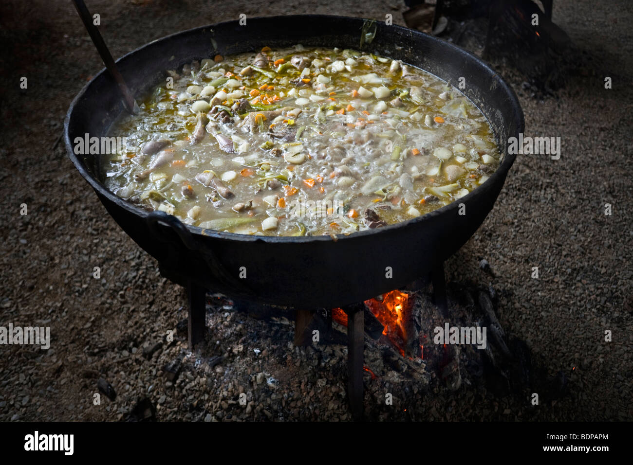 Wood fire cooking of a vegetable soup in a pot. Cuisson au feu de bois d'une soupe de légumes dans une marmite. Stock Photo
