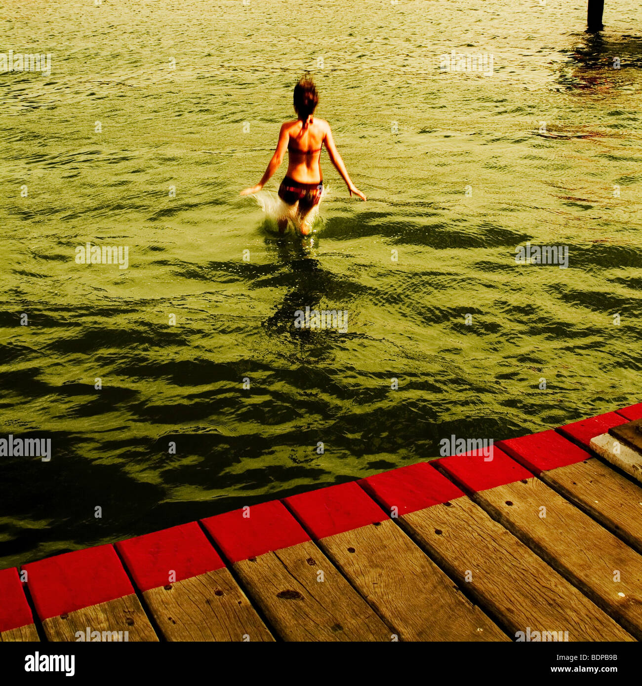 A young girl walking into water near a jetty Stock Photo - Alamy