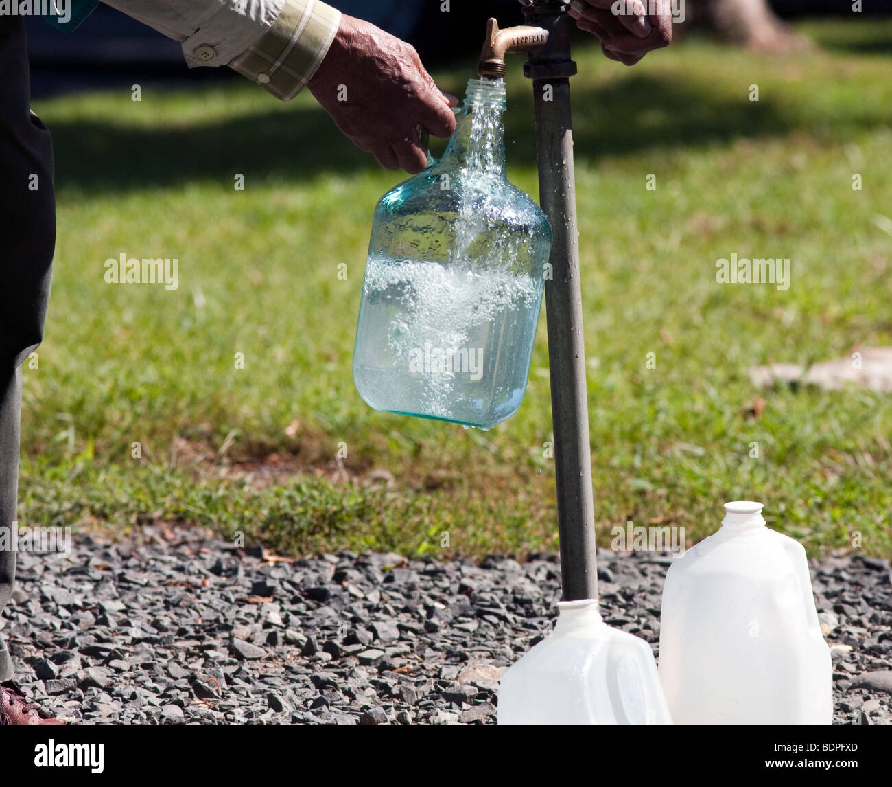 Filling a large glass jug at an outdoor tap with pure clean well water
