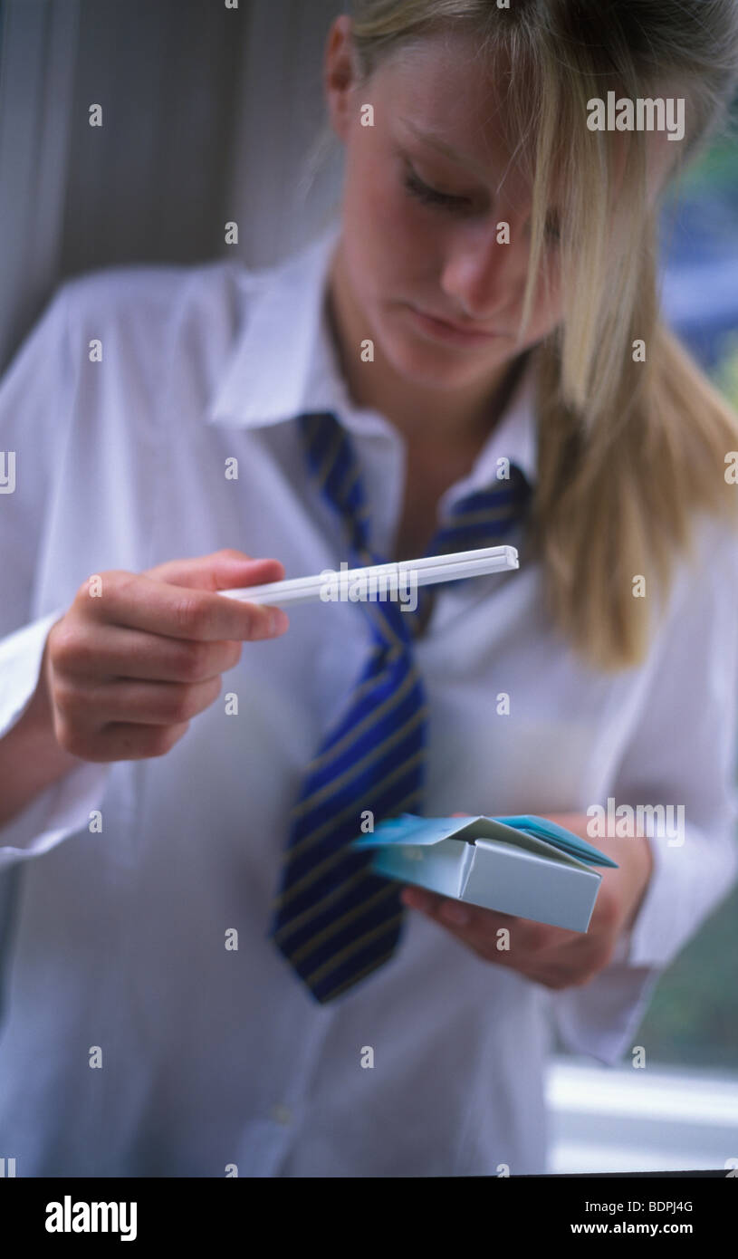 teenage schoolgirl holding a pregnancy test looking worried Stock Photo