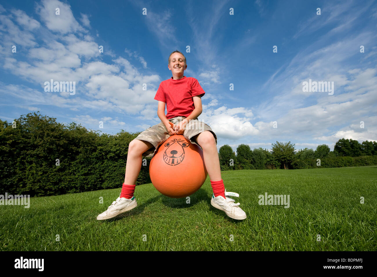 Teenage boy bouncing on a space hopper during summer in England Stock Photo