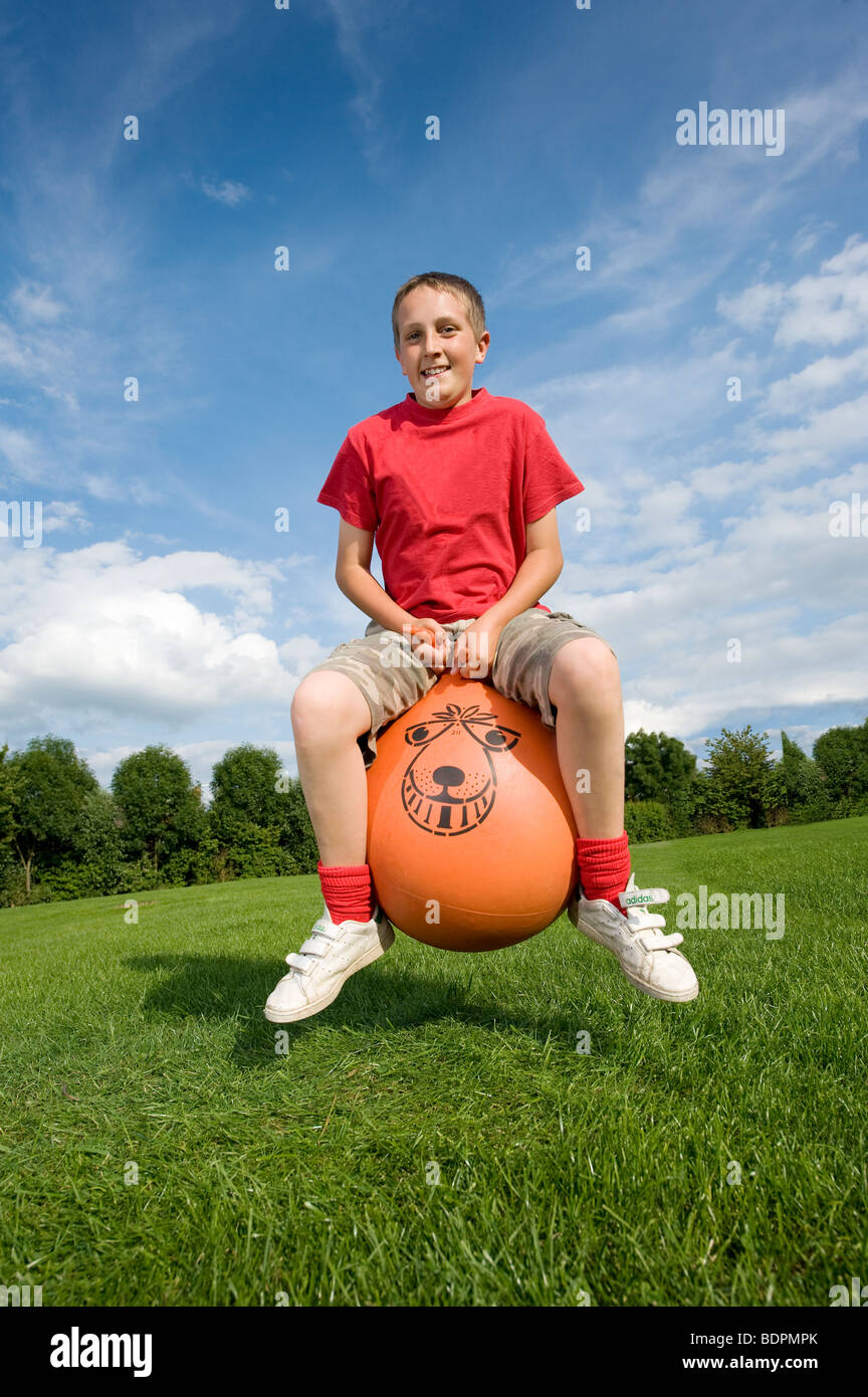 Teenage boy bouncing on a space hopper during summer in England Stock Photo