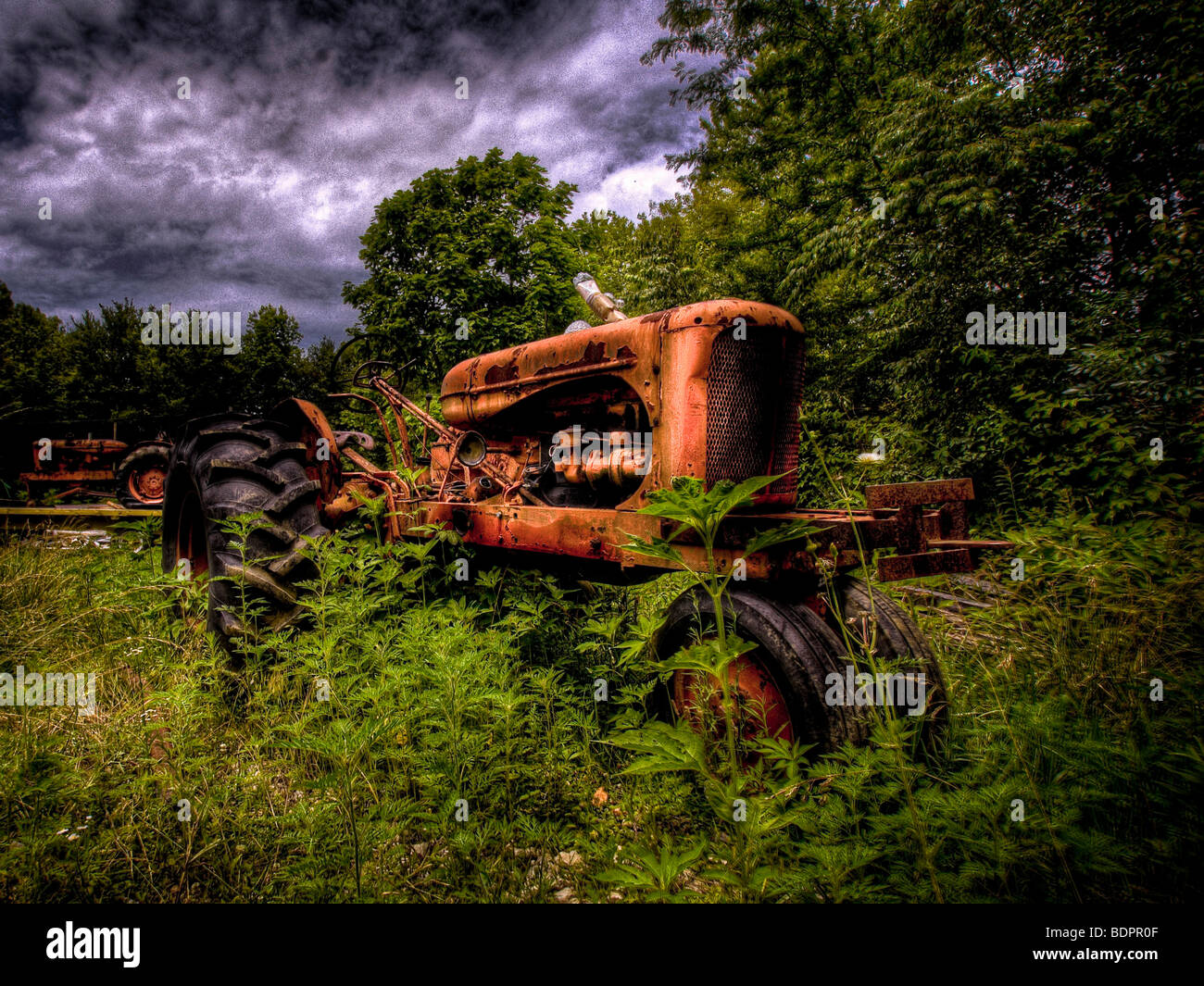 An old red 1950's tractor left to decay in a field Stock Photo