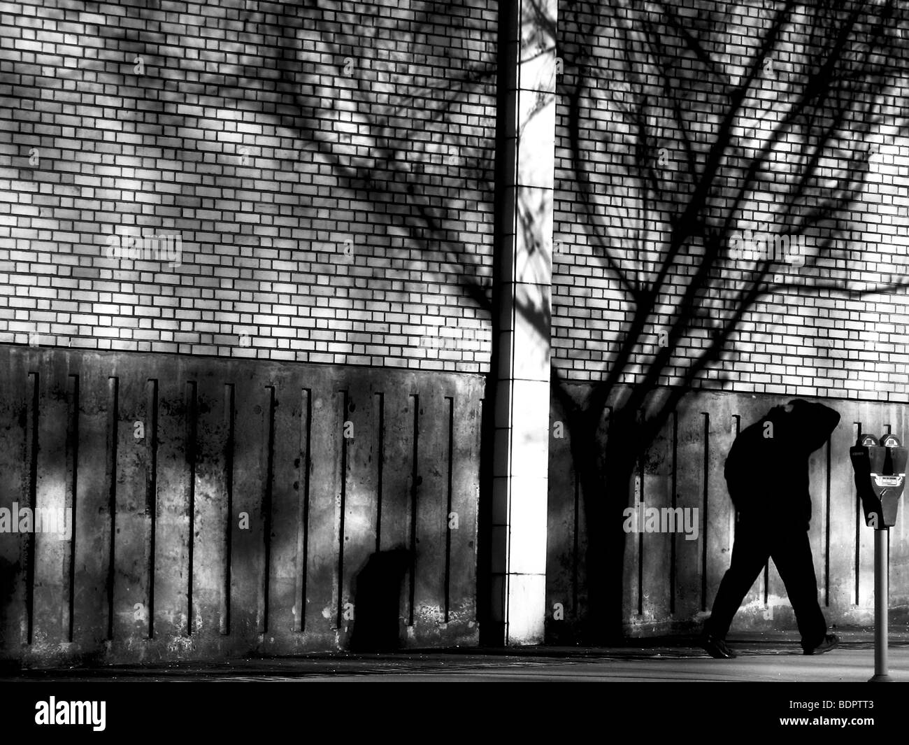 A male figure walking along a path by a building Stock Photo - Alamy