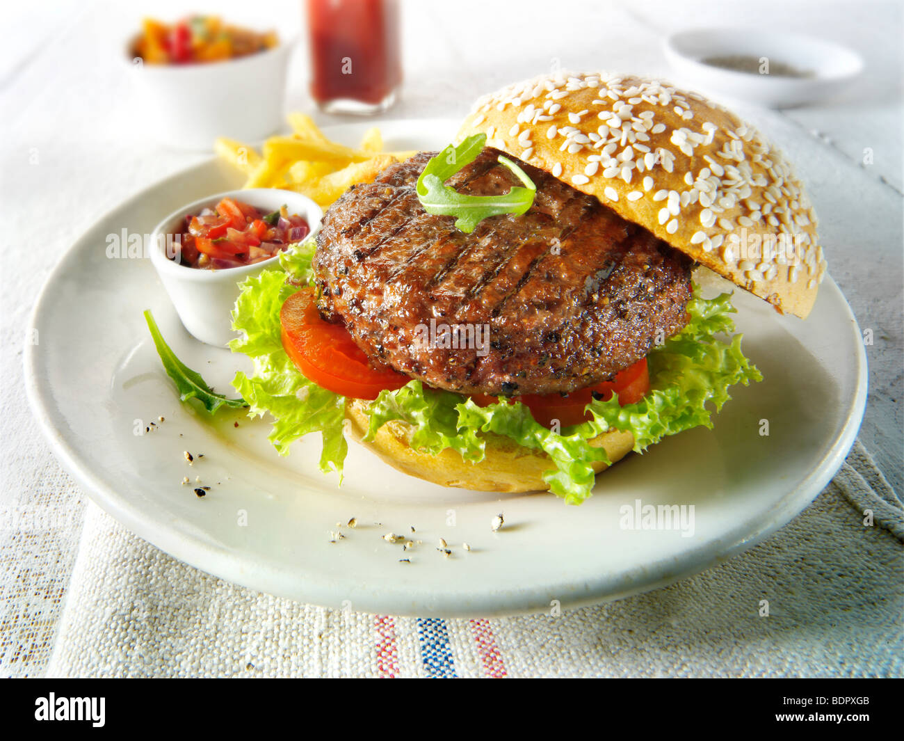 Char grilled beef burger with chips and salad and a seseme bun Stock Photo