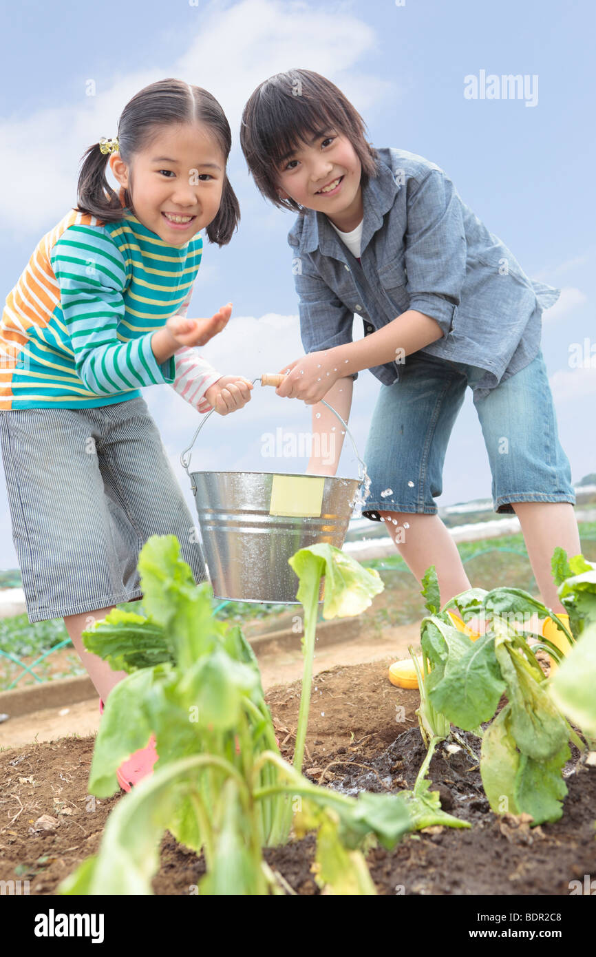 Boy and girl watering field Stock Photo - Alamy