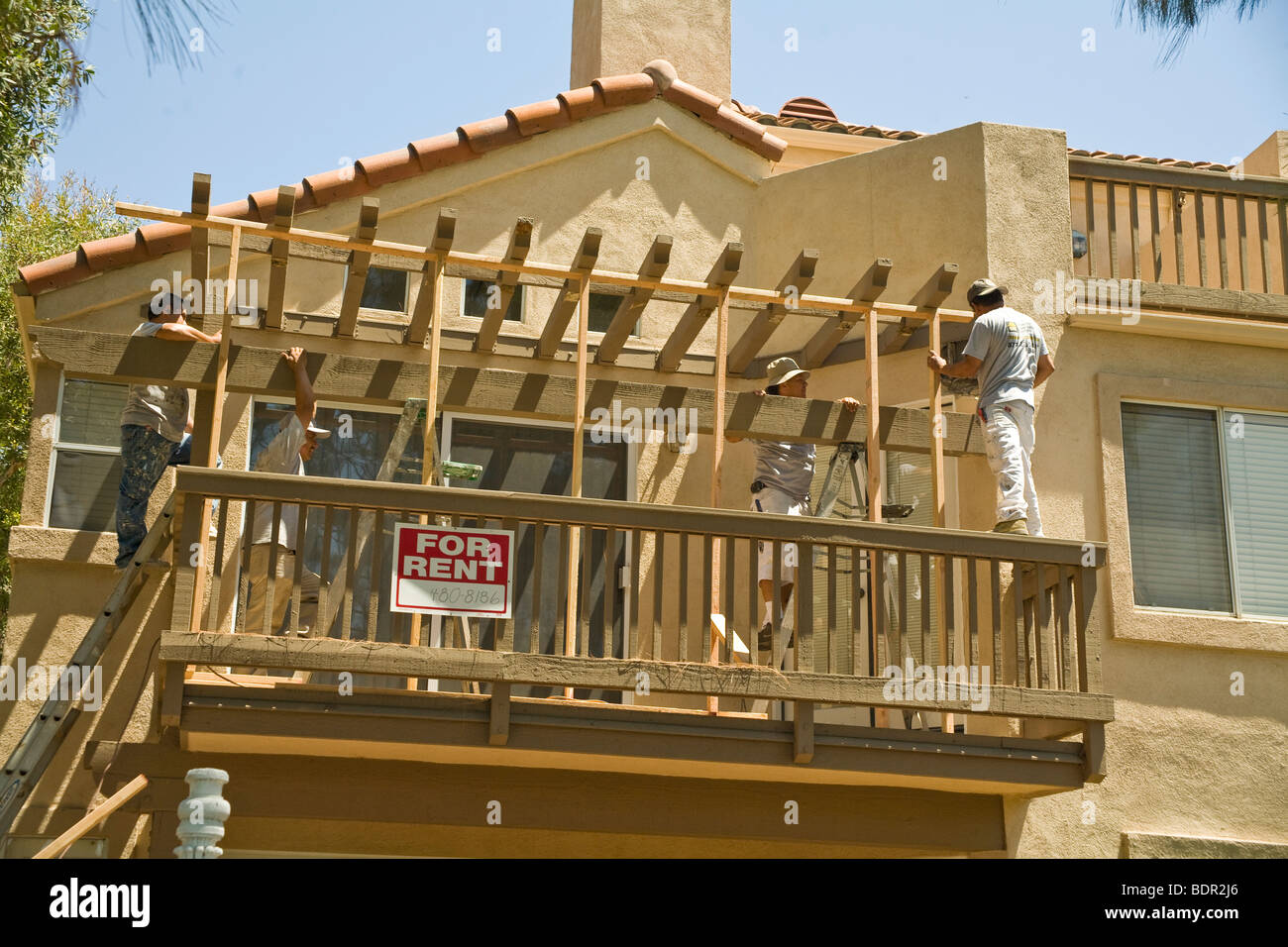 Carpenters replacing termite damaged wood on covered deck of condominium. Stock Photo