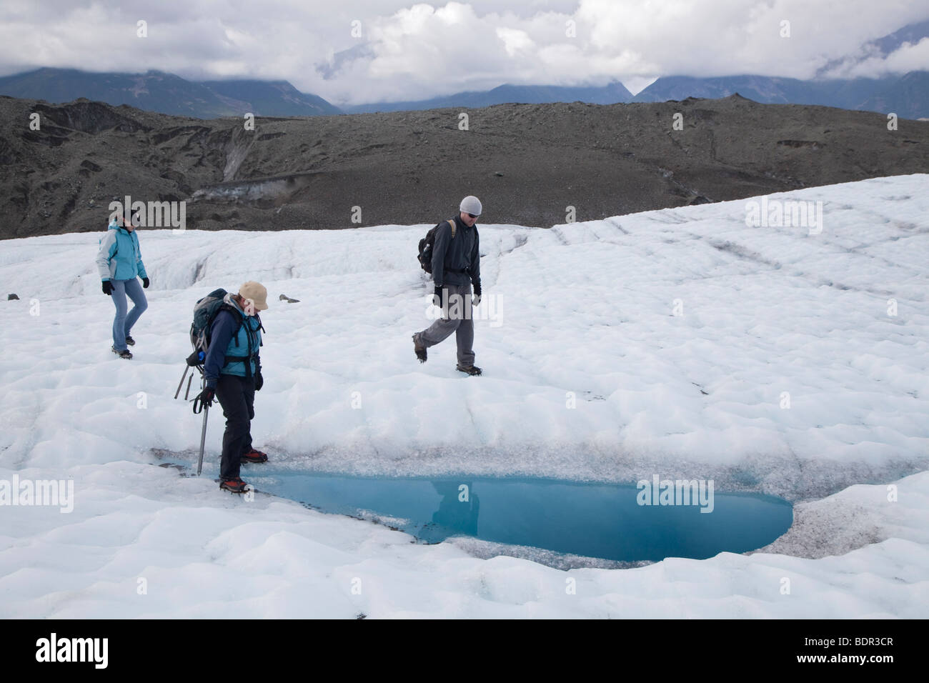 Kennicott, Alaska - Hikers on the Root Glacier in Wrangell-St. Elias National Park examine a pool of meltwater. Stock Photo