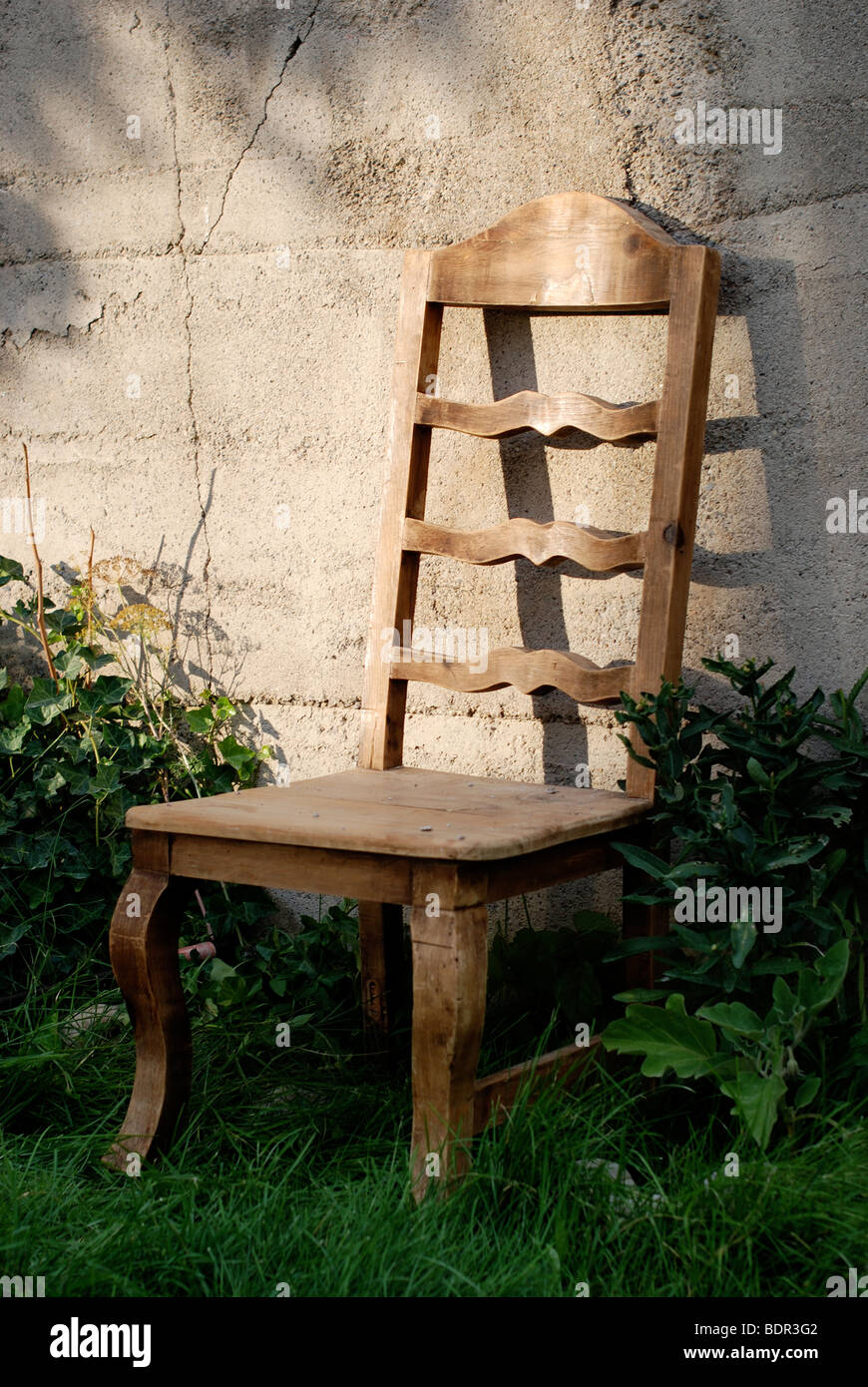 Wooden Chair against concrete wall in evening light. Stock Photo