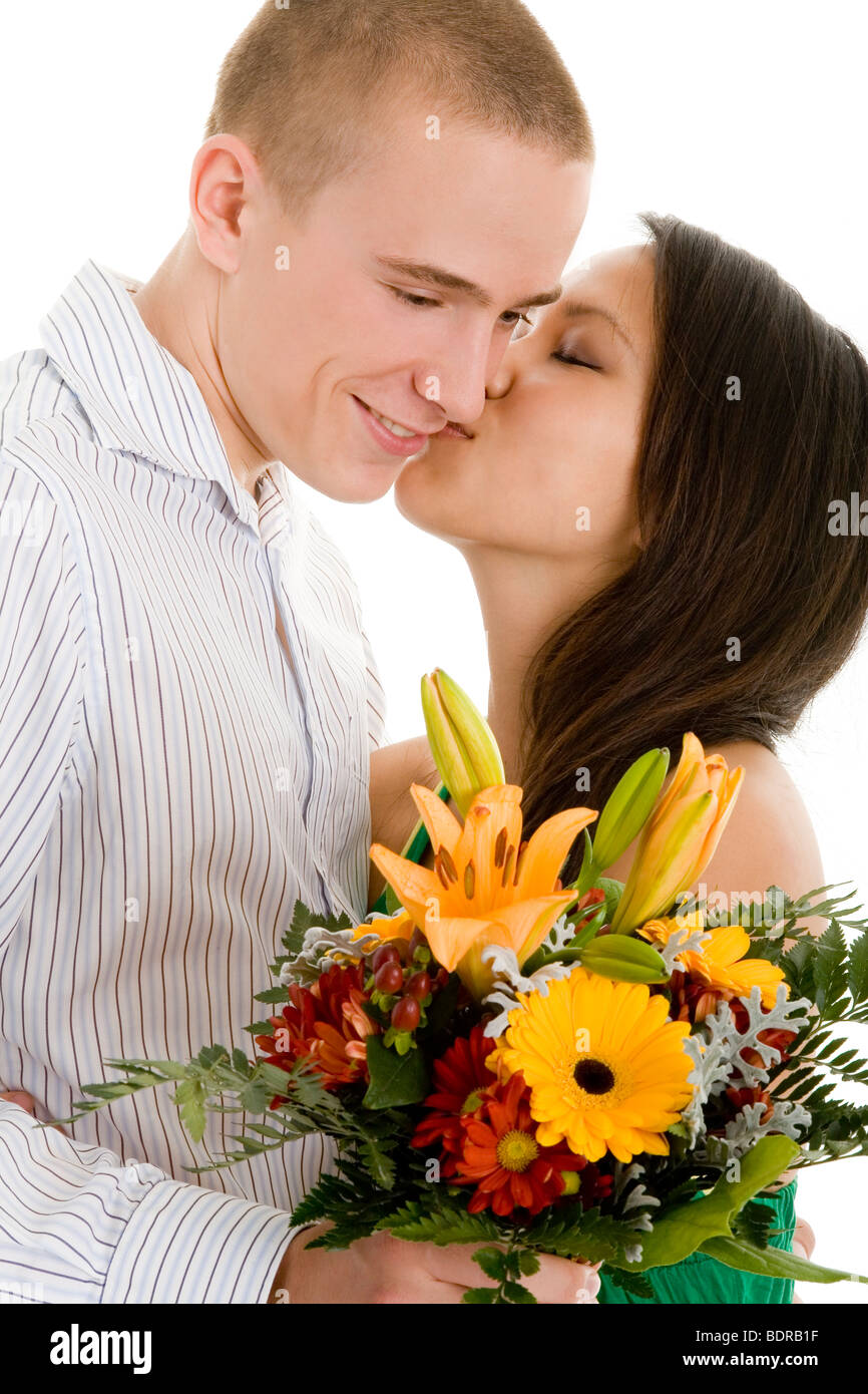 Junge Frau k sst ihen Freund, der ihr einen Blumenstrau reicht Stock Photo