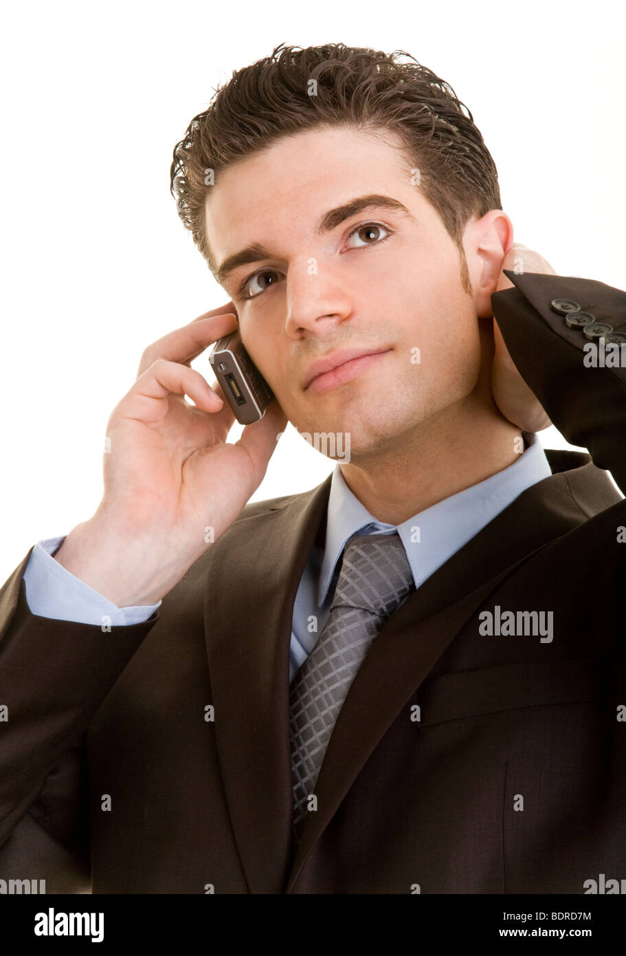 Junger Mann im Anzug telefoniert mit seinem Handy und streicht sich dabei ber die Haare Stock Photo