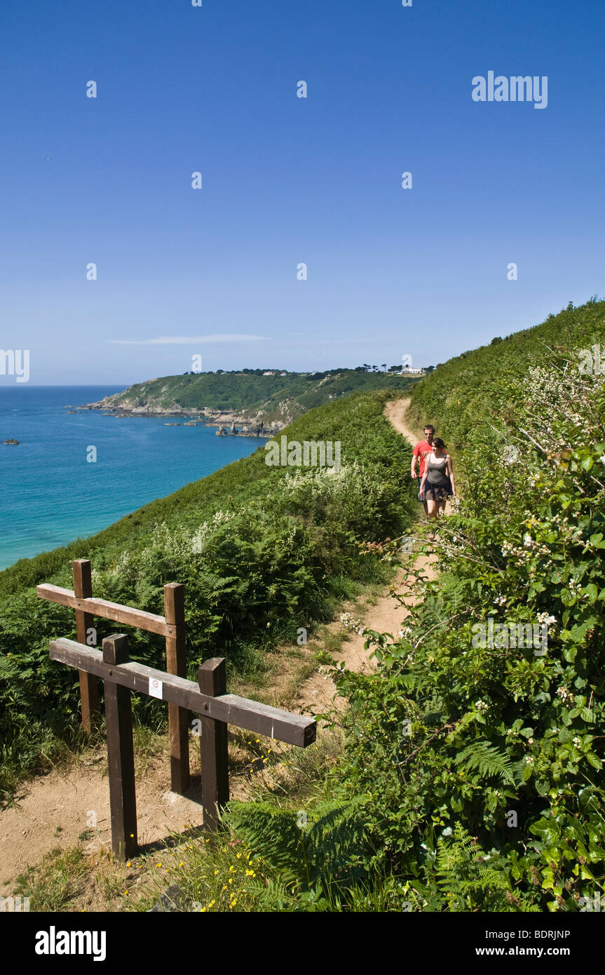 dh Moulin Huet Bay footpath ST MARTIN GUERNSEY South coast gate with young walking couple walkers two walk coastal cliff path Stock Photo
