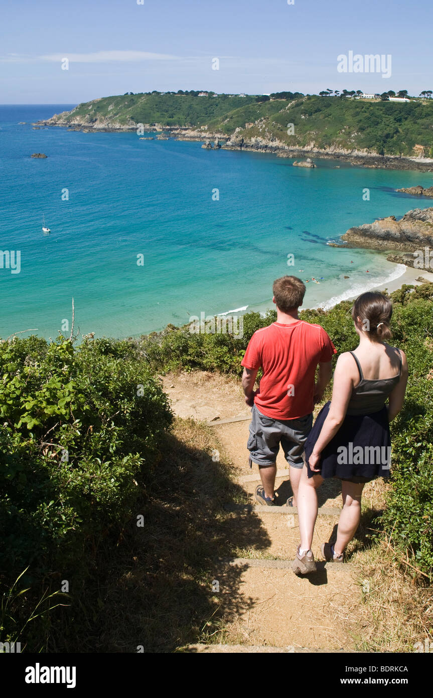 dh Moulin Huet Bay ST MARTIN GUERNSEY Young tourist couple walking down footpath to bay and southern coast two coastal walk cove scenery uk scenic Stock Photo