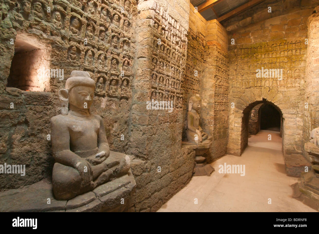 Outer Crypt at Koe Thaung Temple showing some of the many thousands of Buddha carvings in the wall and some of the many Buddha s Stock Photo