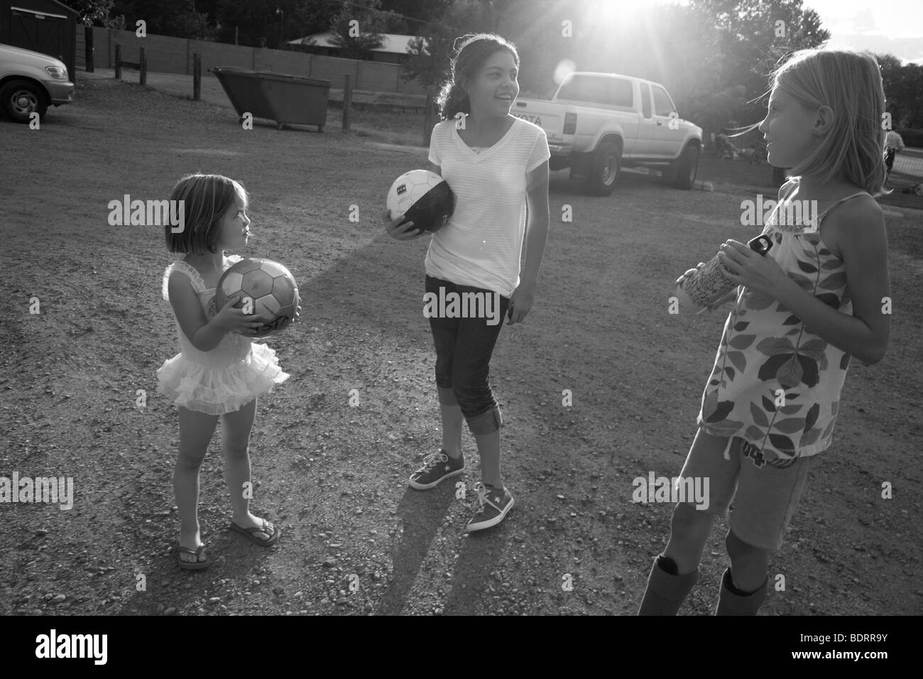 Black and white image of three girls holding soccer ball Stock Photo