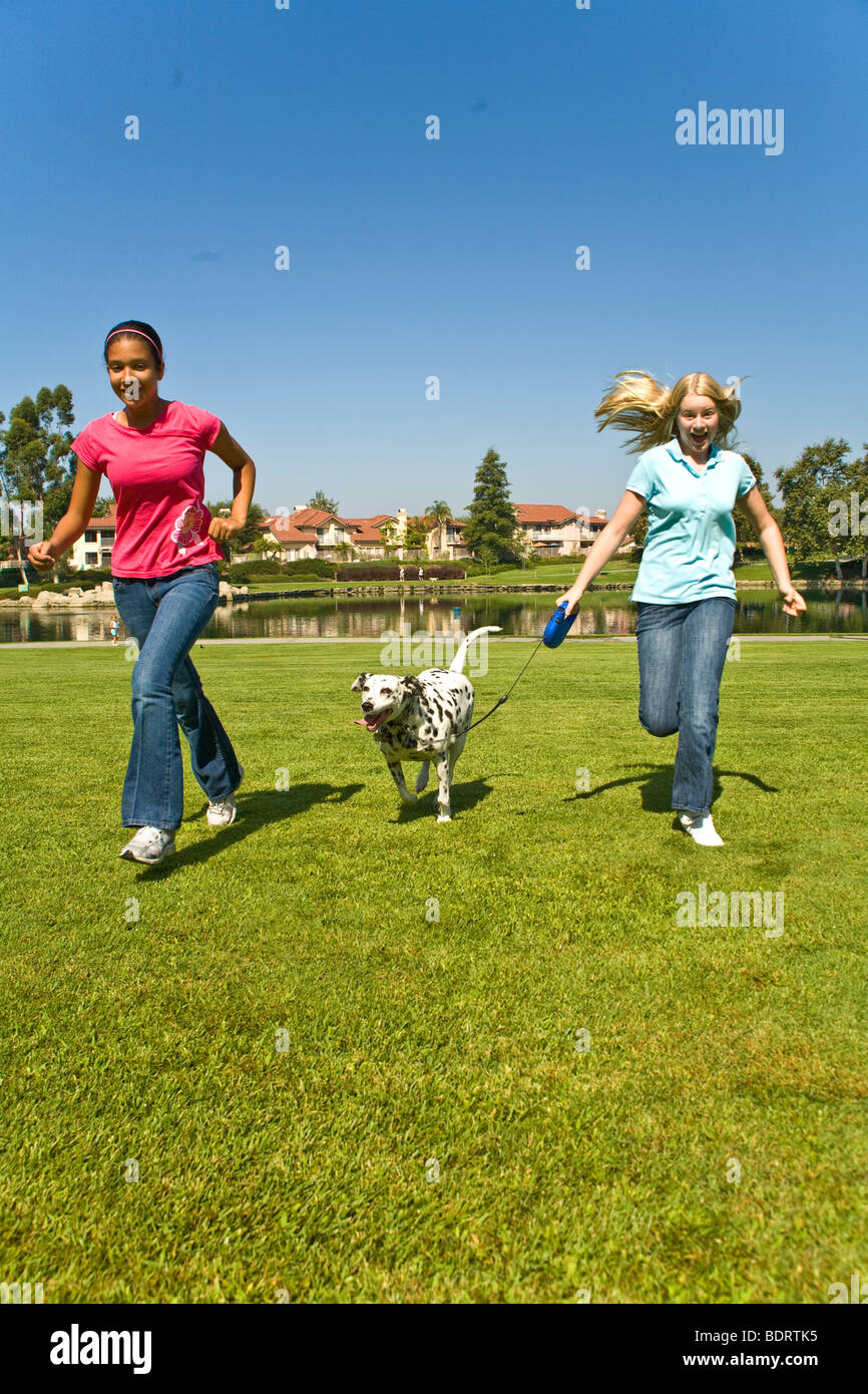 Two Tween tweens diverse girls hang hanging out together Hispanic and Caucasian junior high girls laugh laughing run Dalmatian front USA US MR  © Myrleen Pearson Stock Photo