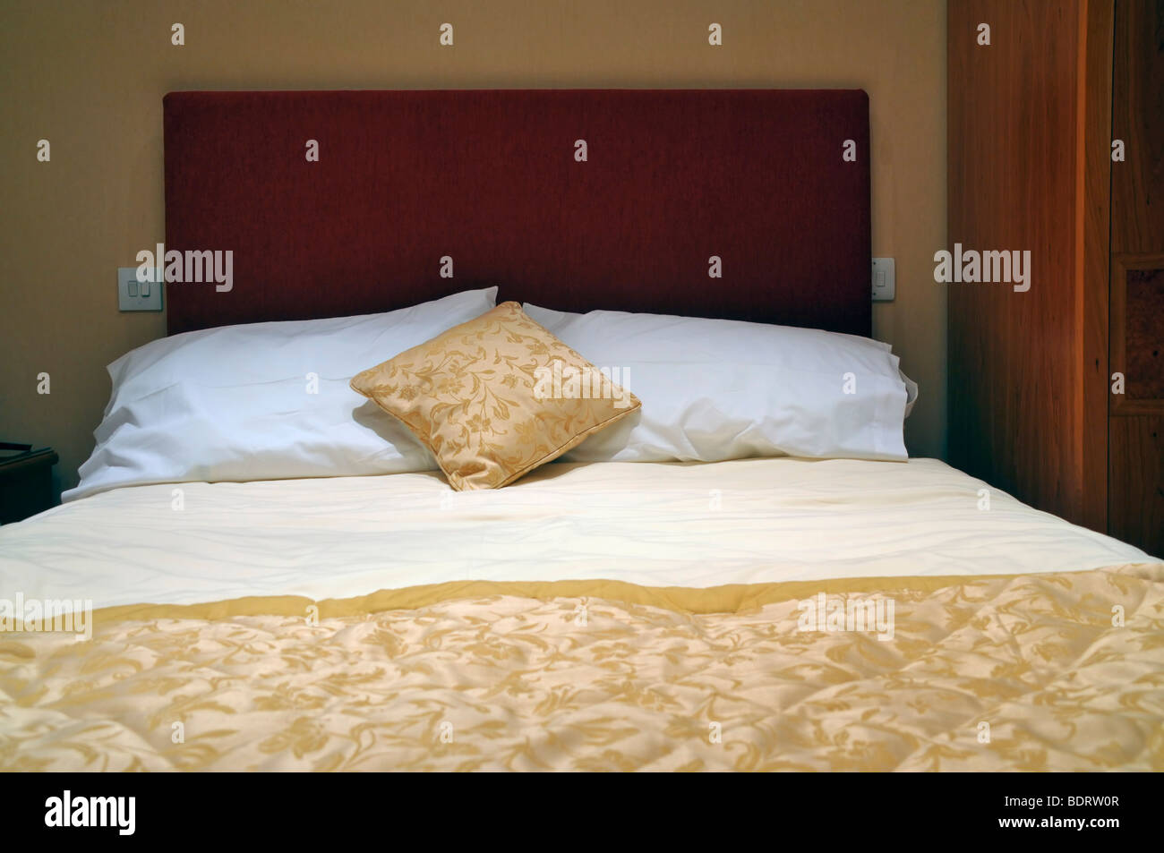 Looking up to the headrest of a made double bed  as seen from the footrest. Stock Photo