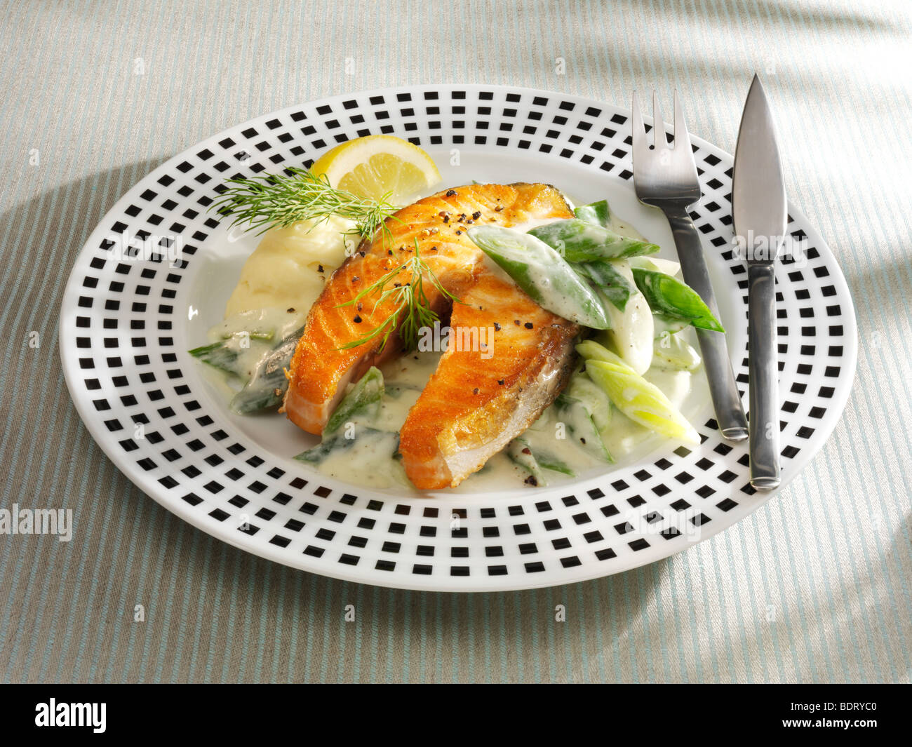 Salmon casserole with vegetables, dill and lemon with fish cutlery on a dotted plate Stock Photo