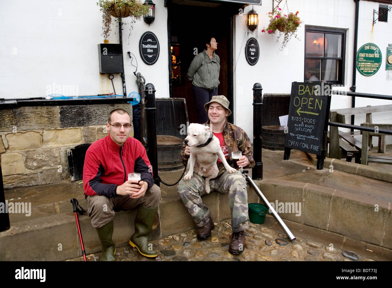 Walkers with their dog outside a pub in Robin Hoods Bay, North Yorkshire, England Stock Photo