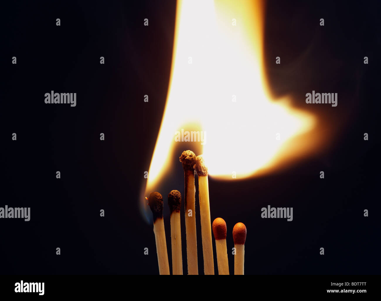 bright flame as four matches are set on fire whilst two shorter ones stay unlit Stock Photo