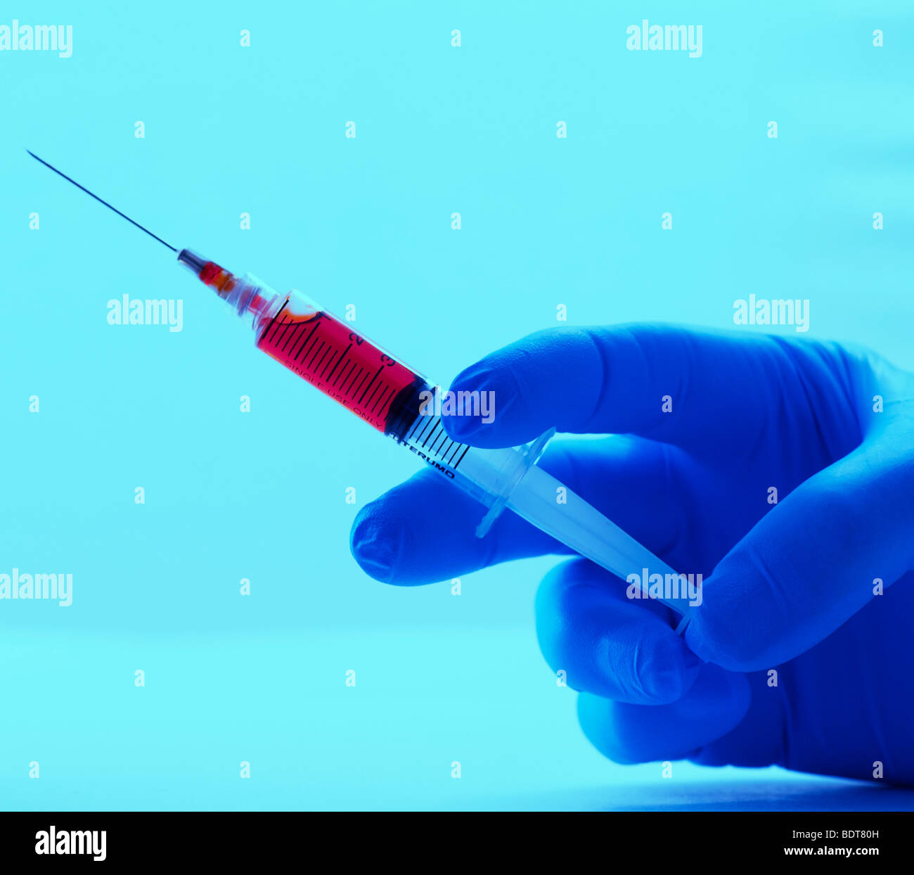 gloved hand holding hypodermic needle Stock Photo