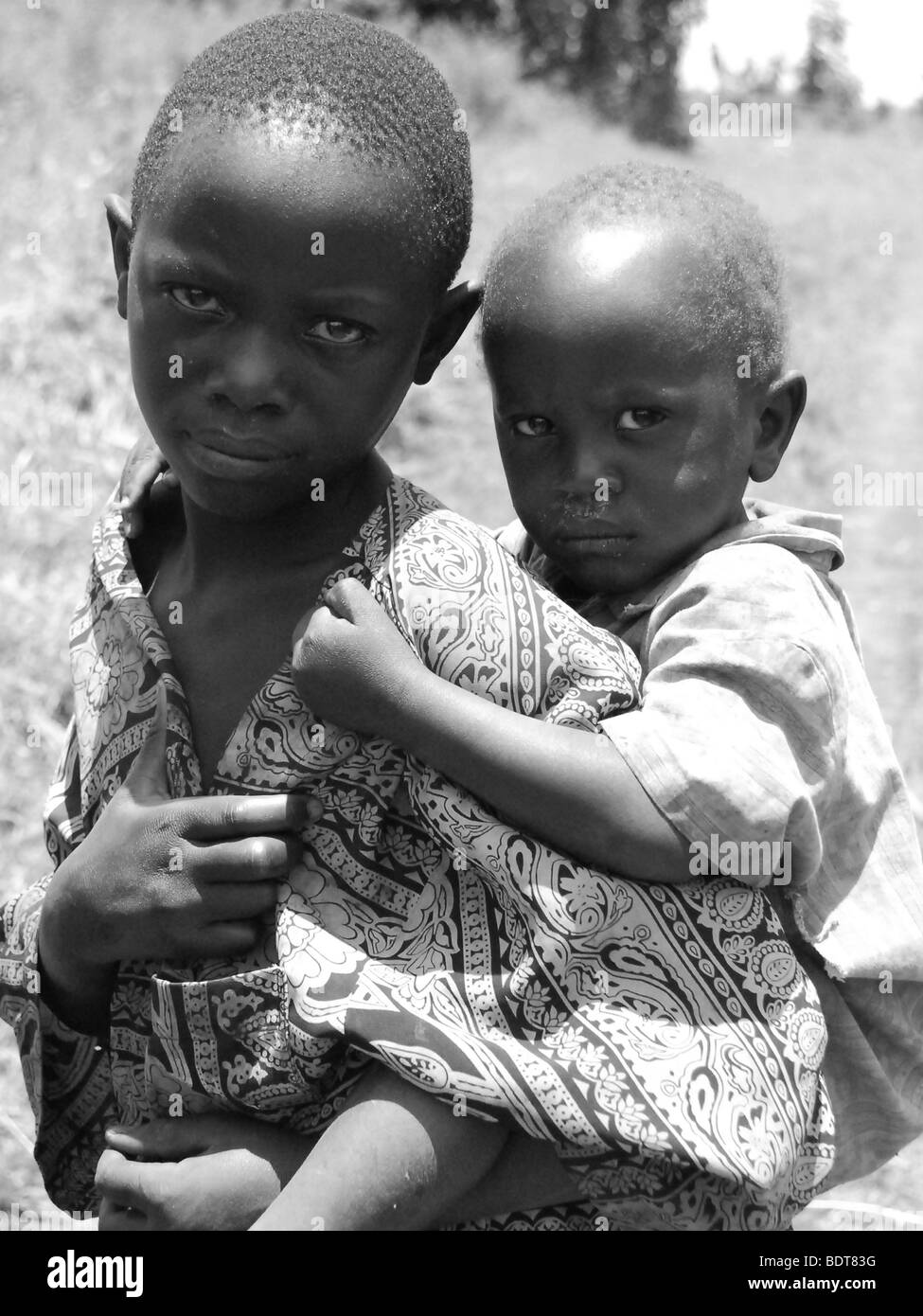 Young children caring for even younger siblings is common place in Africa. This boy in Uganda carries his brother on his back. Stock Photo