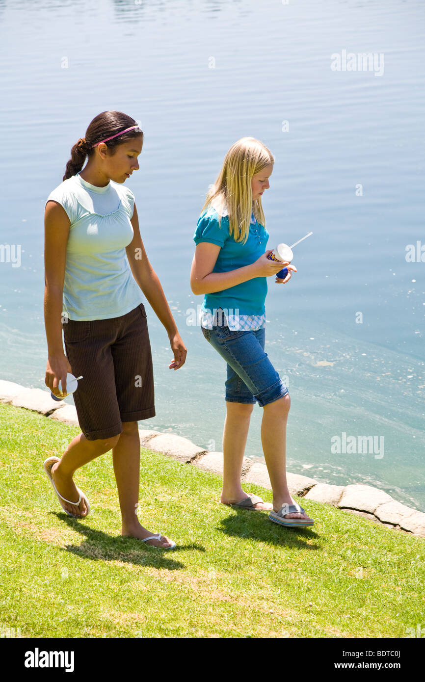 Hispanic and Caucasian Tween tweens age girls walk along edge of lake.  MR Stock Photo
