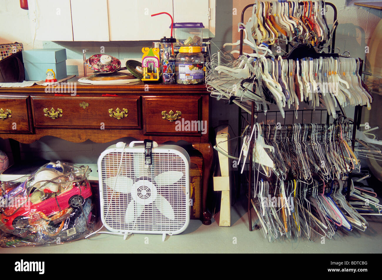 Residential interior Basement storage. Wire clothes hangers on a rack. Floor fan and table in the cellar of a home. Organized clutter Stock Photo