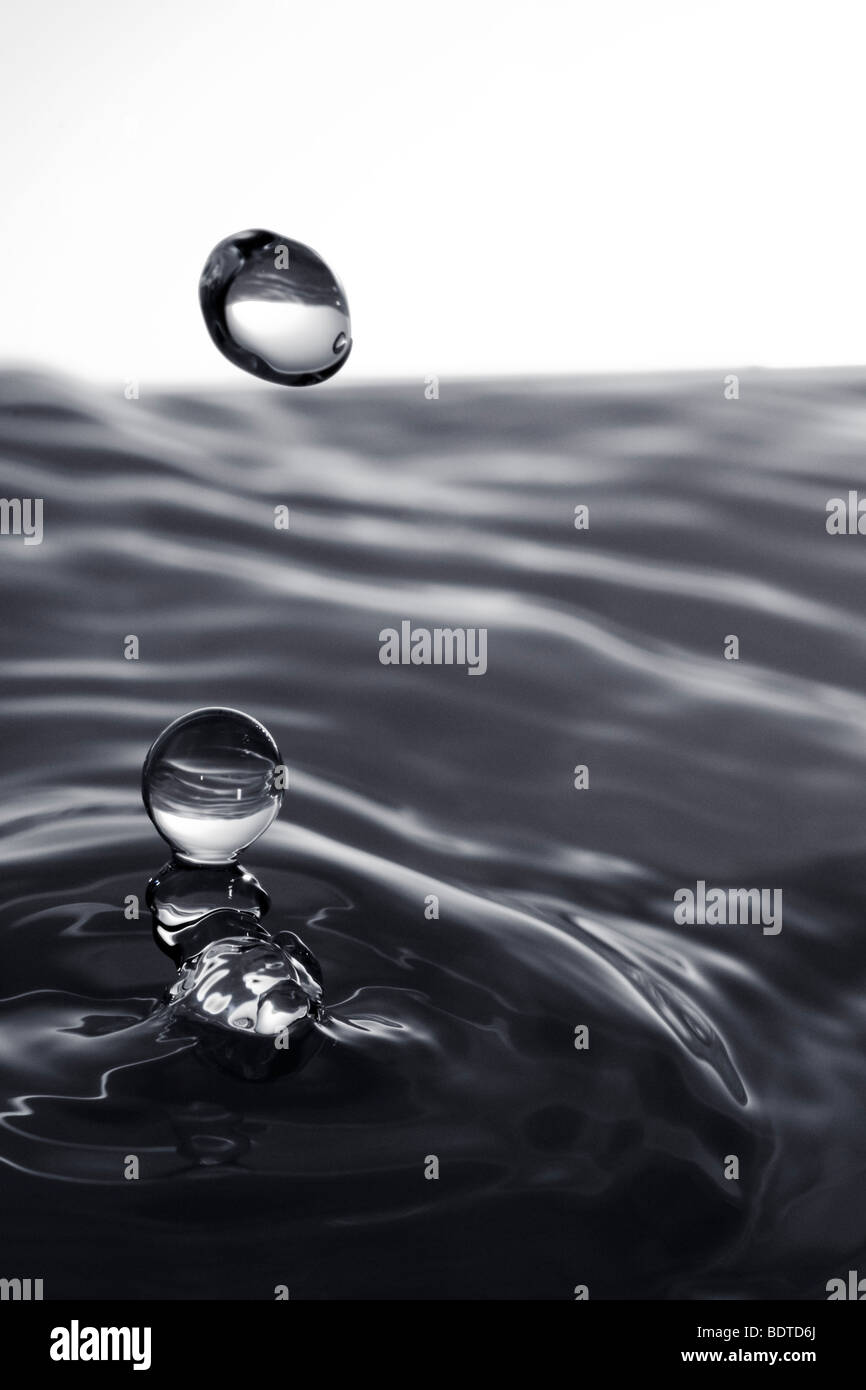 A water drop falling into a pool of liquid. Stock Photo
