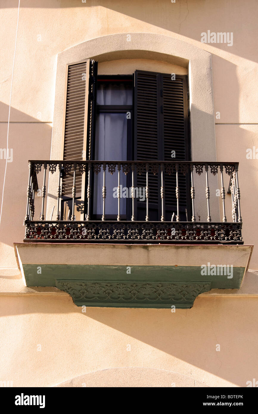 Spanish window with wrought iron balcony and wooden shutters Stock
