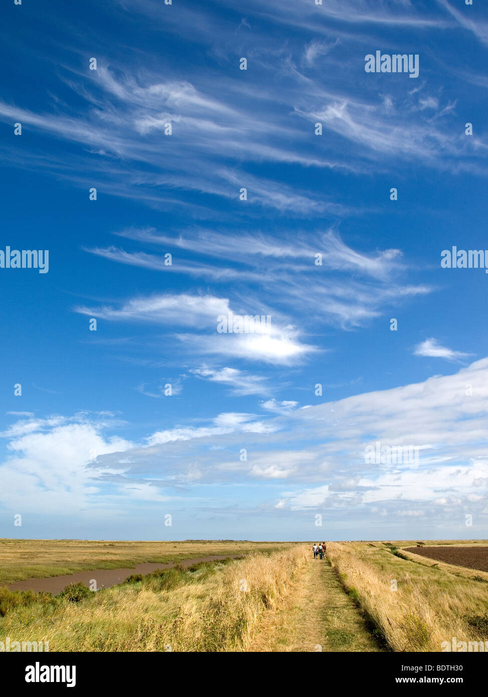 Huge sky where tourists walk over Peddars Way on the Norfolk Coast Path near Brancaster Staithe Stock Photo