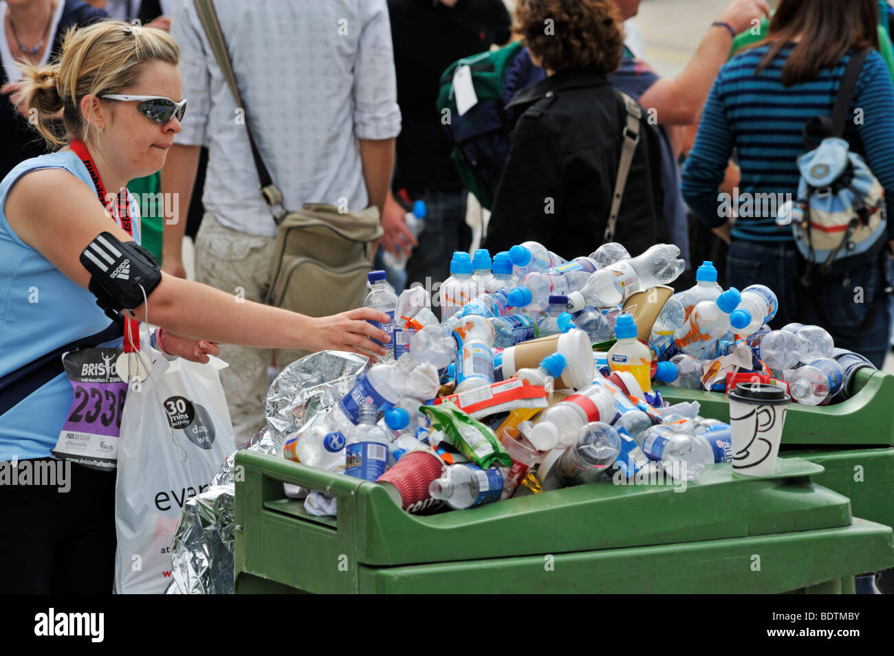 Young woman disposing drinks bottle in bin. Bristol Half Marathon Stock Photo