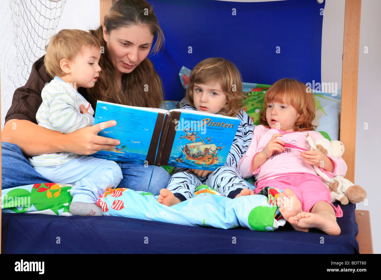 mother reading a book about pirates to her children in a Billi-Bolli loft bed Stock Photo