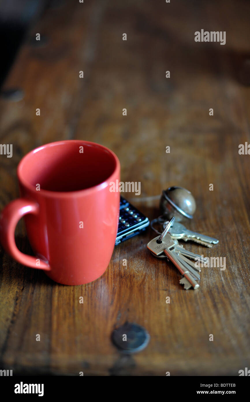 keys and phone next to mug Stock Photo
