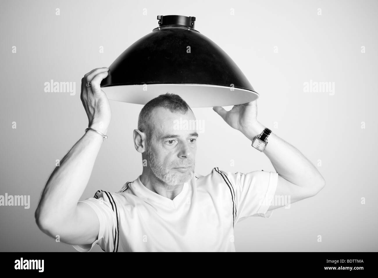 Man with a beauty dish (looks like a light shade) over his head. Stock Photo