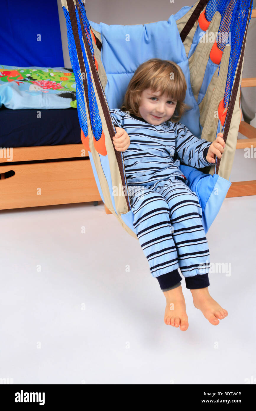 little boy in pyjama in a swing of a Billi-Bolli loft bed Stock Photo
