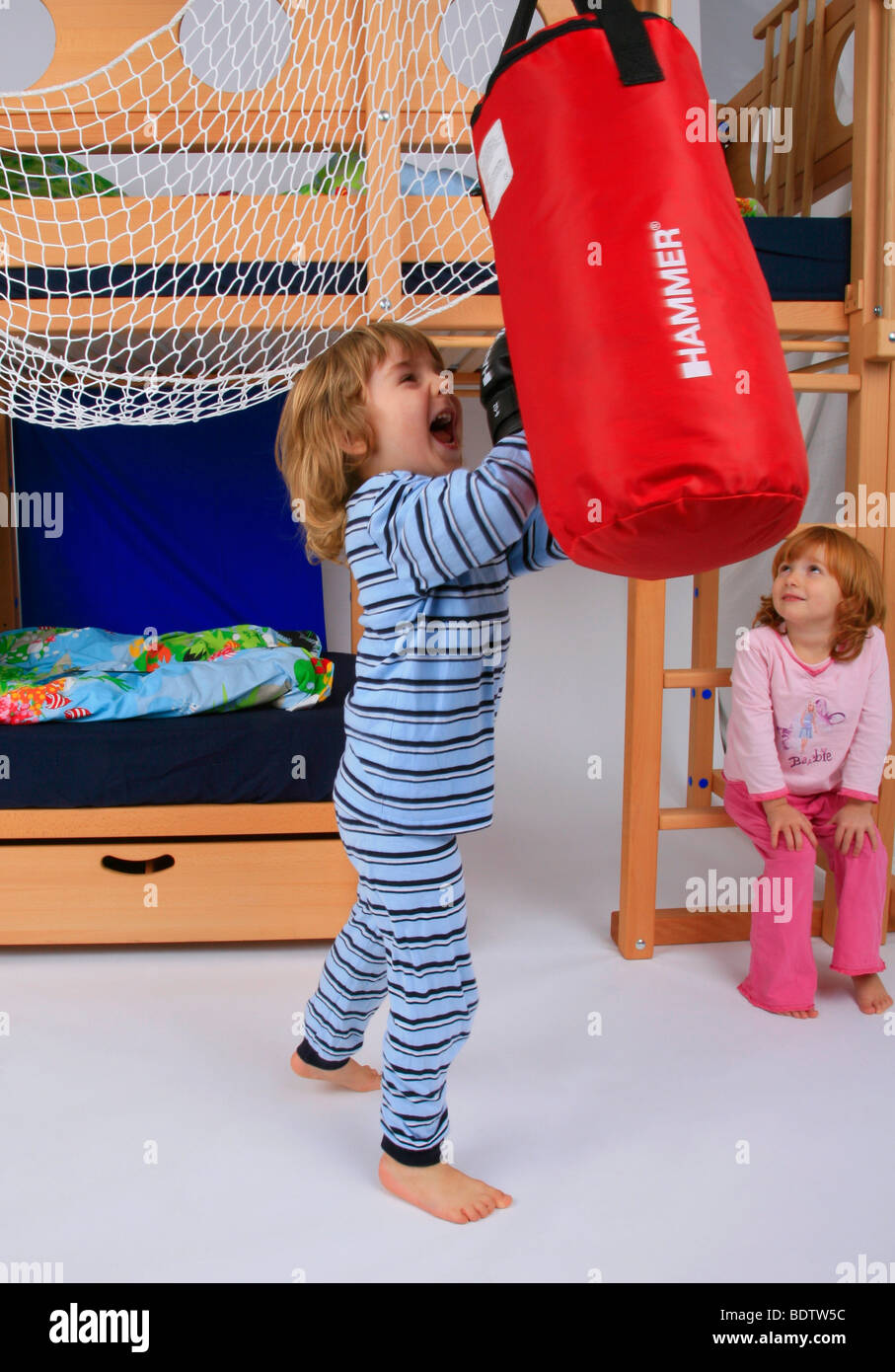 little boy in pyjama training with the punching bag of a Billi-Bolli loft bed Stock Photo