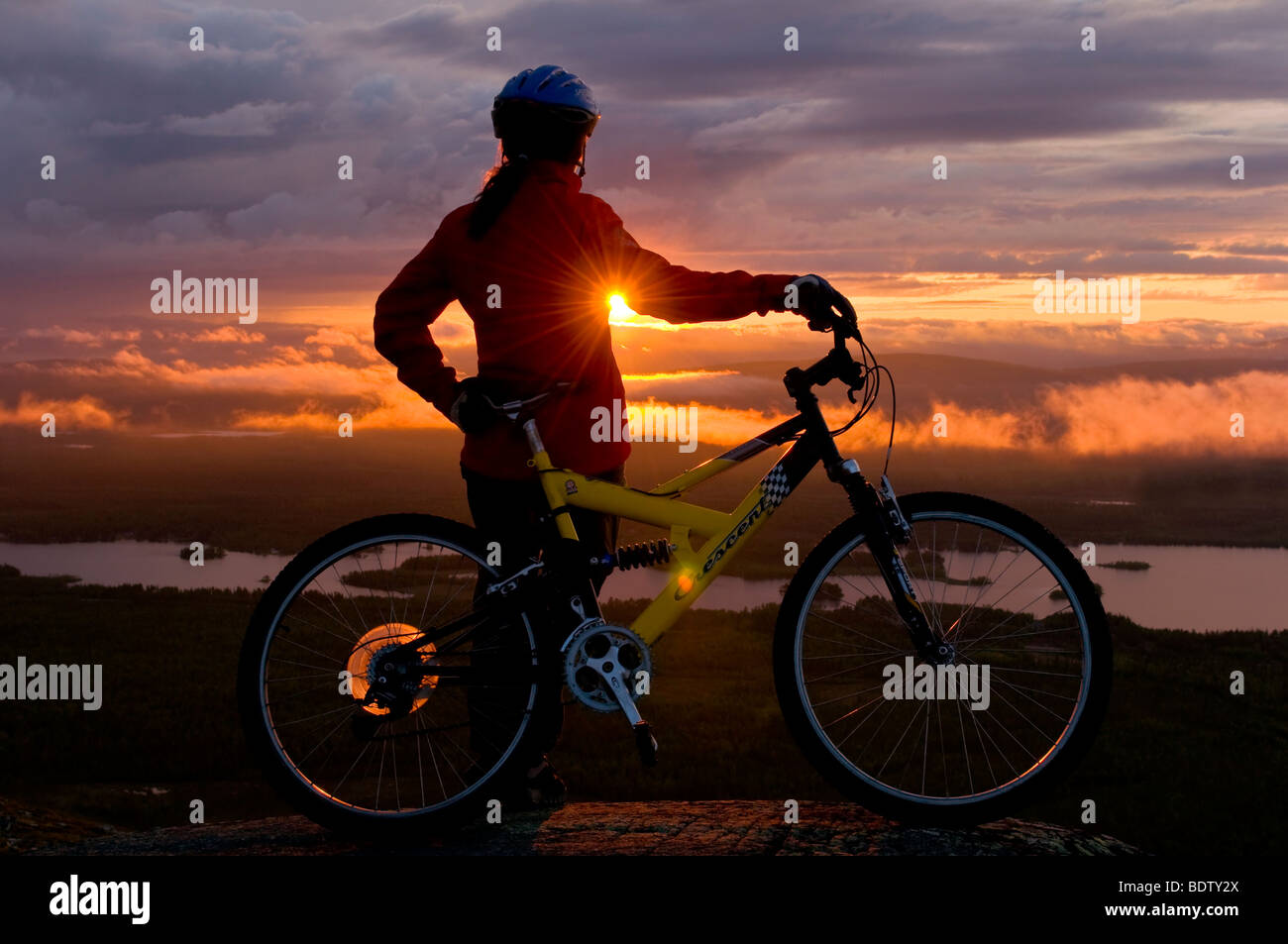female downhill cyclist at midnight sun, lapland, sweden Stock Photo