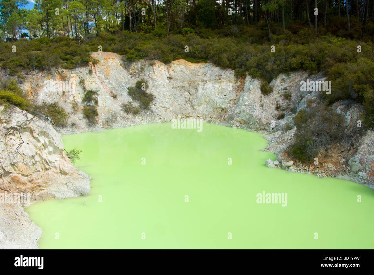 a large ruggedly-edged crater with an amazing green water colour at its base, Waiotapu Geothermal Wonderland, New Zealand Stock Photo