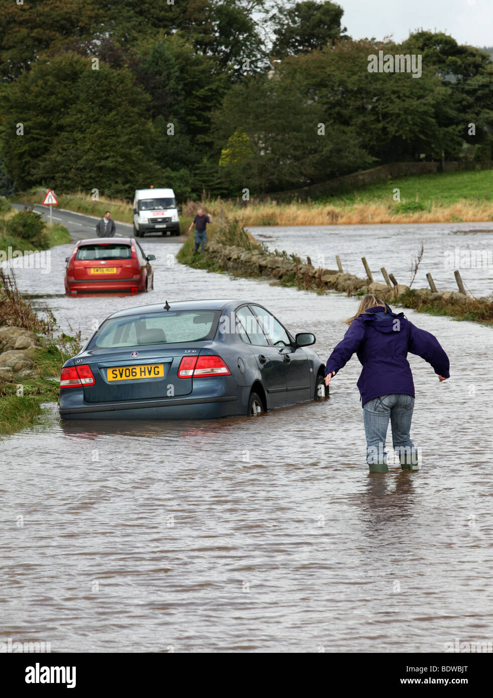 Woman wades out to cars abandoned after being caught in flood water on roads near Aberdeen, Scotland, UK, after heavy rain Stock Photo