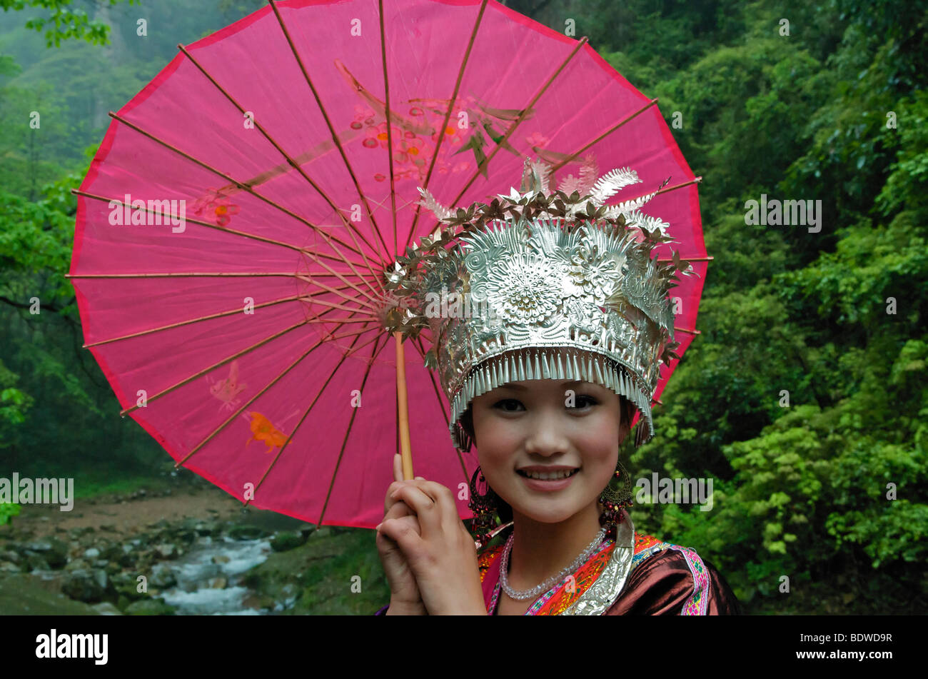 Pretty girl posing in formal Tujia costume holding pink umbrella for photos Wulingyuan Scenic National Park Hunan Province China Stock Photo