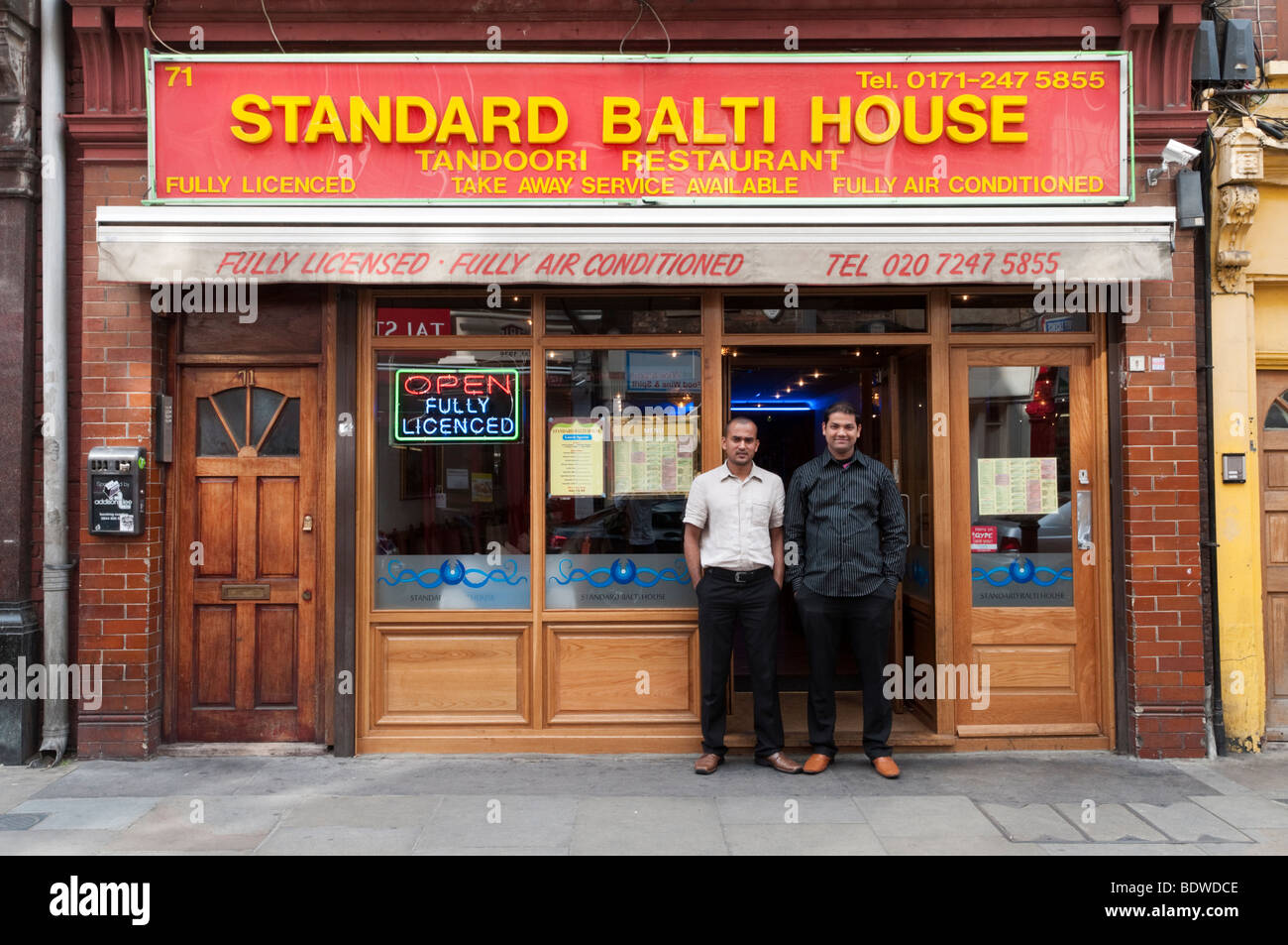 Staff standing outside their Bangladeshi curry and balti restaurant on Brick Lane, Tower Hamlets, London, England, UK Stock Photo