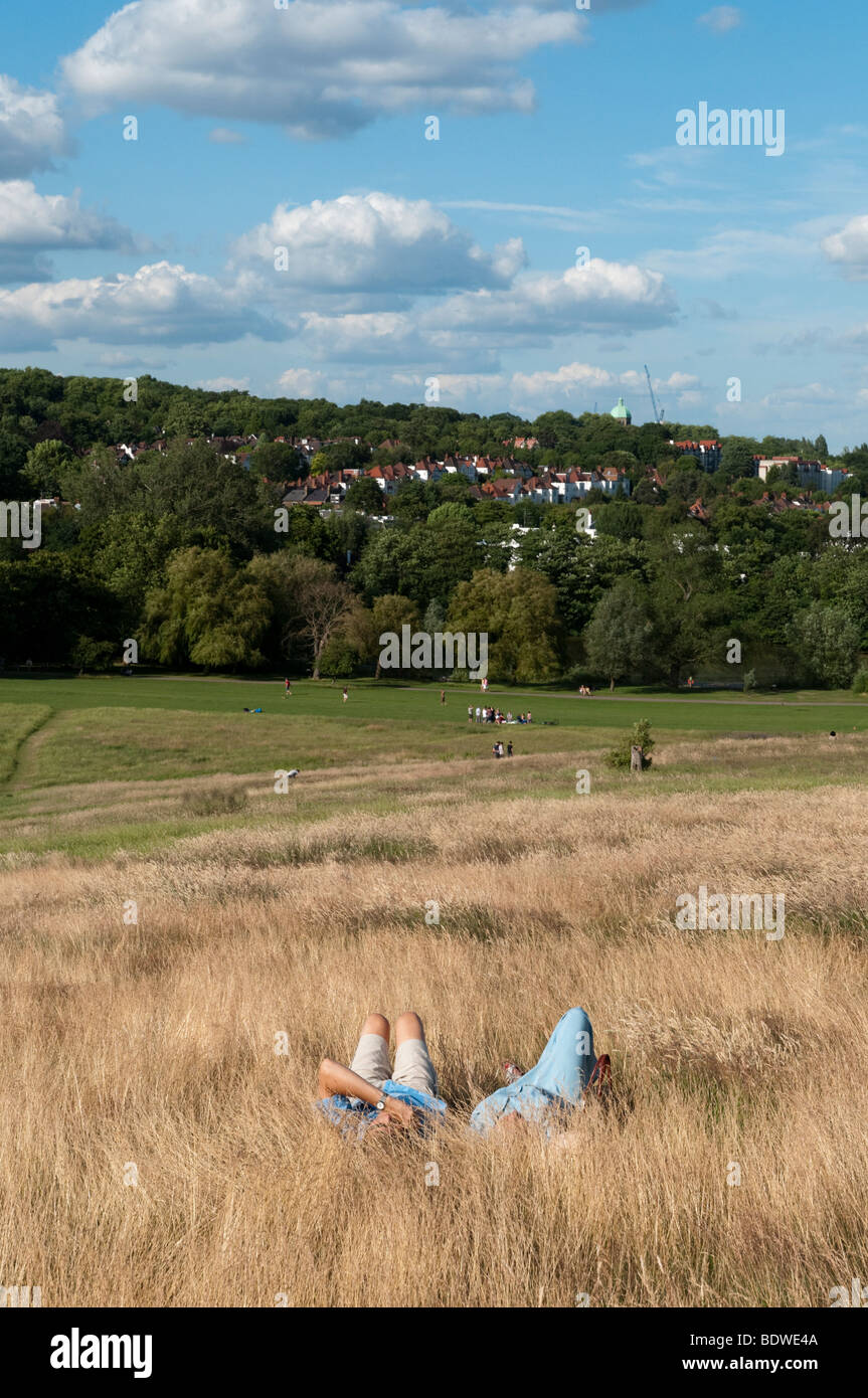Couple relaxing in long grass on Hampstead Heath, London, England, UK Stock Photo