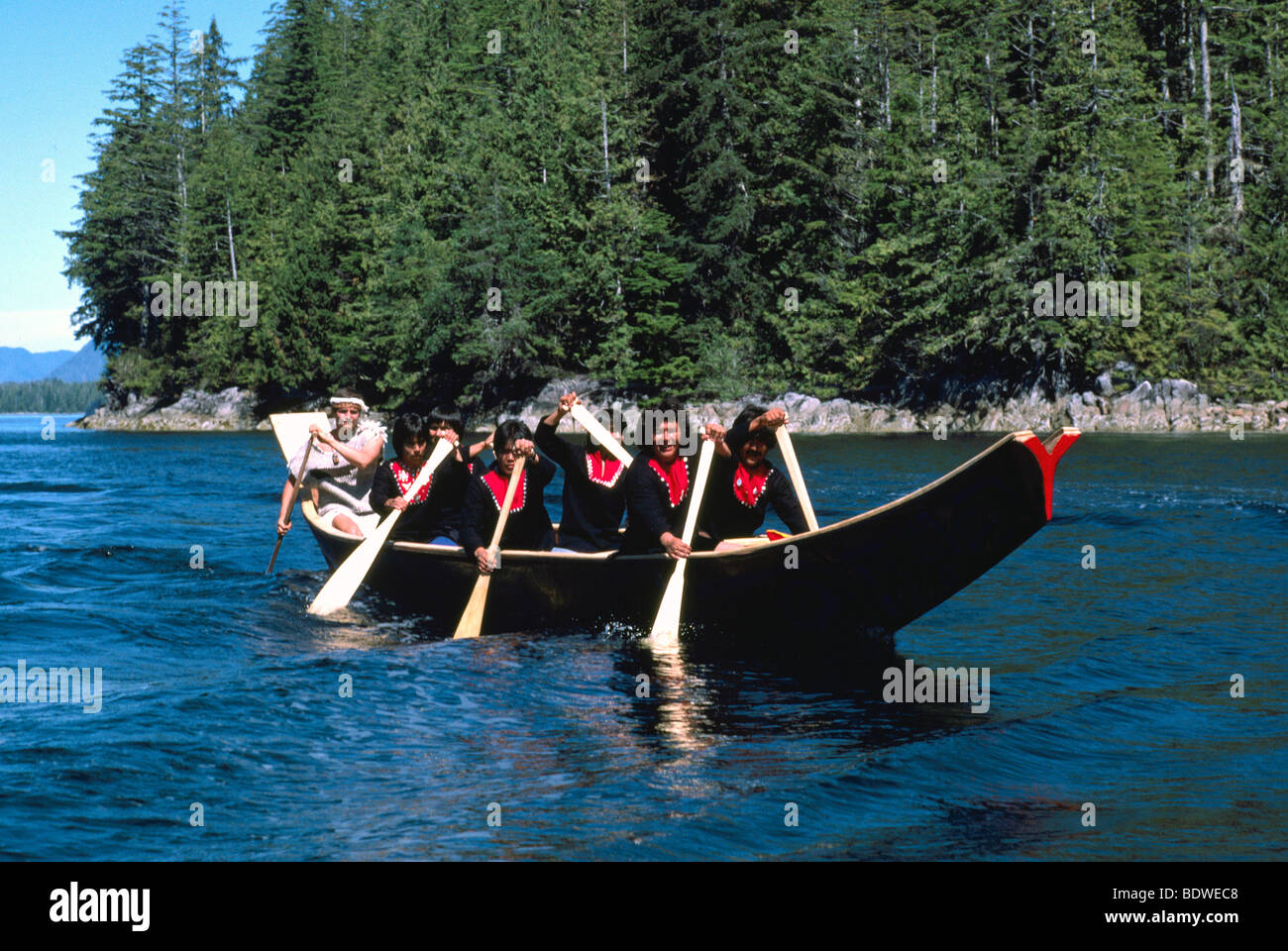 Native American Indians canoeing in a Traditional Dugout Canoe near Bella Bella on the West Coast of British Columbia Canada Stock Photo