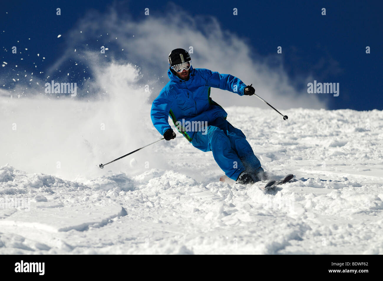 Skier moving down on ski slope against blue sky. Stock Photo